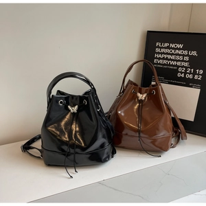 Detail of glossy faux leather bucket backpacks with metal butterfly drawstring toggles