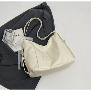 Close-up of a cream PU leather tote bag with number embossing and lace ribbon detail