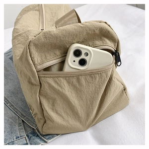 Khaki nylon travel bag detail showing side zipper pocket holding a mobile phone