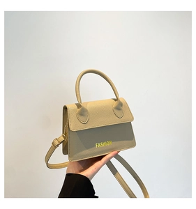 Detail of beige litchi grain leather crossbody bag with top handle and golden hardware