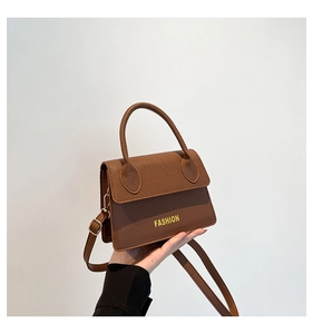Close-up of brown litchi grain leather texture and yellow Fashion text on handbag