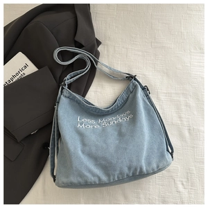 Détail du sac hobo en jean bleu clair avec broderie blanche Less Mondays More Sundays