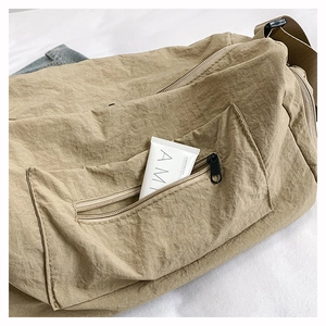 Detail of khaki nylon bag with black zipper pocket showing spacious internal storage