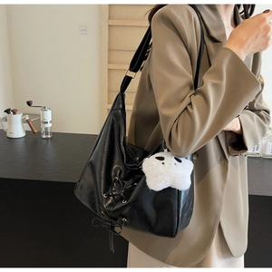 Detail of black commute tote bag featuring side lace-up design and star plush pendant