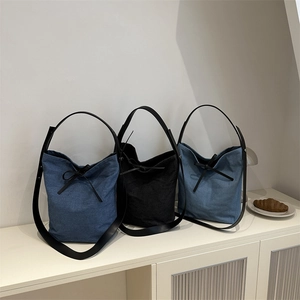 Three minimalist denim bucket bags in dark blue, black, and light blue with leather handles