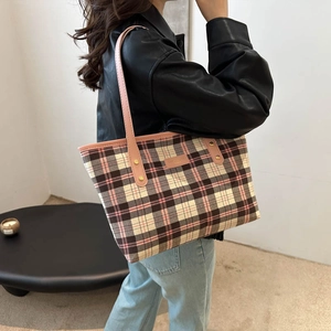 Chic pink plaid tote bag with leather straps and gold rivets shown on a stylish model