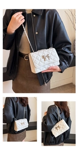Close-up of quilted white crossbody bag featuring silver bow detail and chain strap