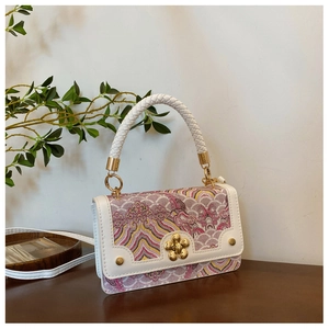 Detail of white leather shoulder bag with pink floral brocade and gold flower clasp