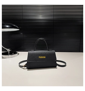 Close-up of black pebble grain square bag featuring a gold FASHION logo on the flap