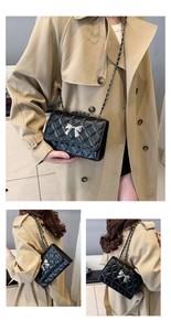 Close-up of black quilted crossbody bag with silver bow buckle and chain strap on model
