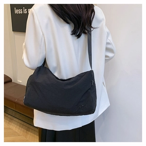 Close-up of black nylon crossbody bag featuring fashion zipper detail and logo