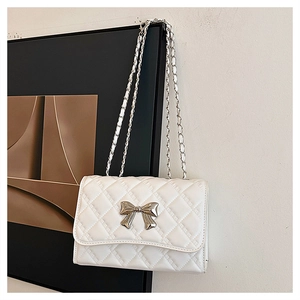 Detail of white quilted leather texture with silver bow clasp and chain strap