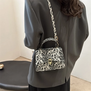 Fashionable leopard print small square bag with gold clasp shown on a grey blazer