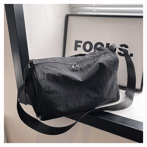 Detail of minimalist black nylon crossbody bag featuring dual zippers and textured fabric