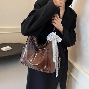 Brown patent leather tote bag with embossed number 10 and white lace bow pendant