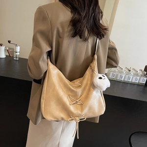 Beige oversized hobo bag with ribbon lacing and plush pendant for daily commute