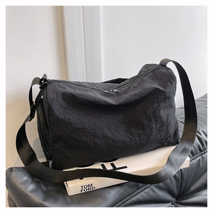 Detail of black nylon barrel crossbody bag featuring a branded fashion strap and side zipper