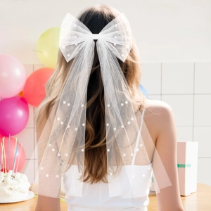 Elegant white bow hair veil with pearls shown from the back on a bride with flowing ribbons