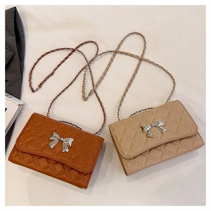 Close-up of quilted chain bags in caramel brown and beige with silver bow details