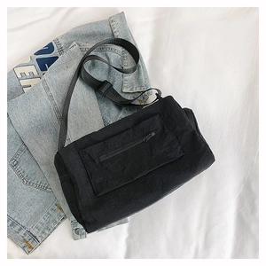 Detail view of the black nylon crossbody bag featuring a front zipper pocket and strap