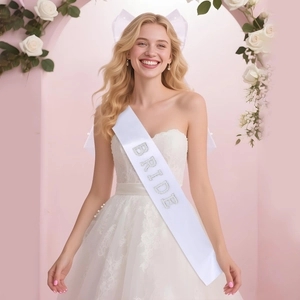 Detailed view of white bridal sash with silver BRIDE lettering and bow veil accessory