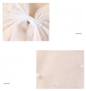 Detail shot of white bridal tulle bow with delicate pearl embellishments for weddings