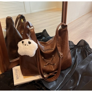 Détail du sac hobo en similicuir marron foncé avec laçage et pendentif panda