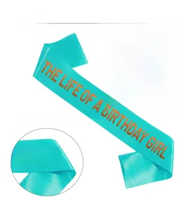 Detail of teal satin sash showing orange gold foil lettering and premium fabric texture