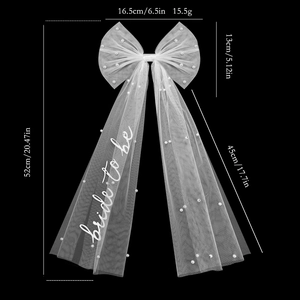 White bridal bow hair clip with pearls and long tulle veil featuring bride to be text