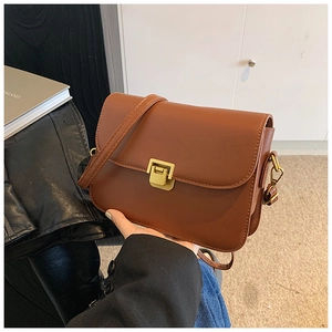 Close-up of caramel faux leather square bag with vintage gold metal clasp detail