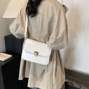 Minimalist white leather crossbody square bag with gold metal clasp shown on model