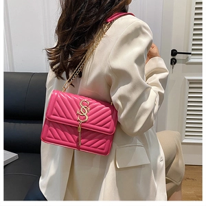 Detail view of pink quilted crossbody bag with gold S-logo and metal tassel fringe