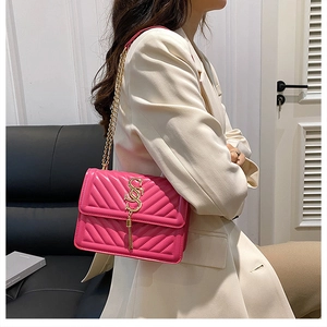 Detail of pink quilted crossbody bag with gold letter S logo and chain strap on model