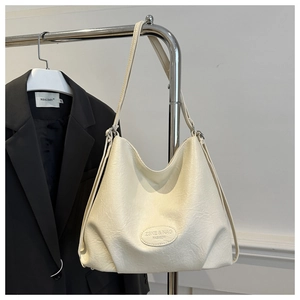 Detail of creamy white leather tote bag featuring embossed logo and grain texture
