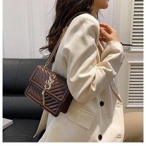 Detailed view of dark brown quilted leather crossbody bag with gold tassel logo