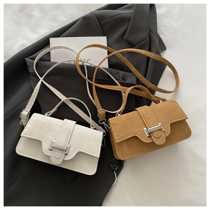 Detail of white and khaki pleated crossbody bags with silver H-buckle on a dark blazer
