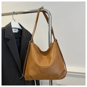 Detailed close-up of brown pebbled leather Hobo bag with embossed logo on metal hanger