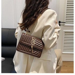Detailed back view of a dark brown quilted crossbody bag with gold chain strap on model