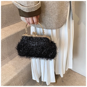 Detail of black fuzzy bag with gold metal handle held by model in warm indoor light