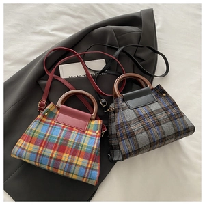 Détail de sacs en laine à carreaux avec poignées en bois et finitions dorées chic