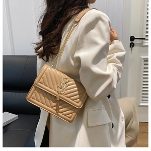 Detail of khaki quilted crossbody bag with gold chain strap and decorative tassel