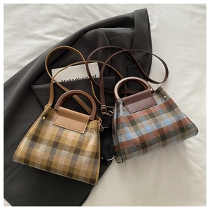 Détail de sacs à carreaux en laine avec rivets métalliques et poignées en cuir