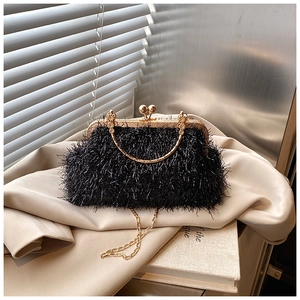 Close-up of black feather evening handbag with gold chain strap on stylish trench coat