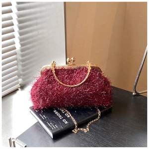 Detail of burgundy glitter evening bag with gold metal handle and spherical clasp