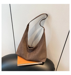 Detail view of a vintage dark brown suede hobo bag on an orange book and leather stool