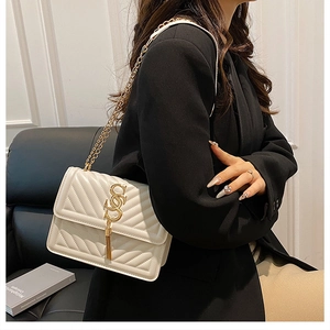 Detail of ivory quilted crossbody bag with golden metal S logo and elegant chain strap