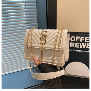 Close-up of white quilted crossbody bag with gold S-logo hardware and elegant tassel