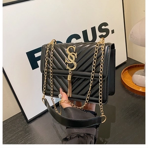 Close-up of black V-quilted chain bag with gold SS logo and elegant tassel detail