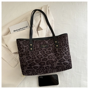 Macro detail of leopard print tote bag with gold rivets and black leather straps