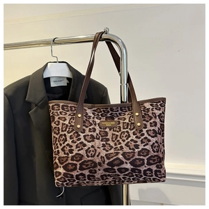 Detailed view of leopard print tote bag with brown leather handles and gold metal rivets